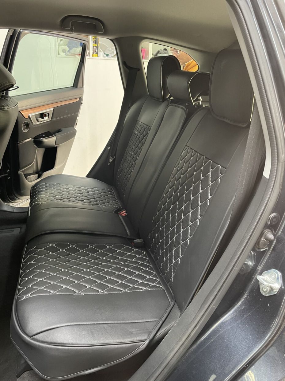 Background of black leather car seat upholstery with rhombus pattern and red stitch lines